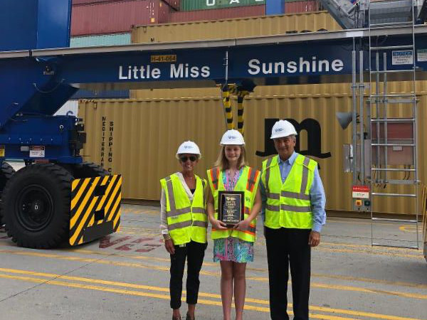 SCPA COO Barbara Melvin (from left), fifth grader Haven Ebel and SCPA CEO Jim Newsome stand beside the rubber-tired gantry crane Ebel named “Little Miss Sunshine
