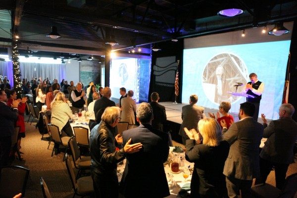 Event attendees stand in honor of John LaRue at Thursday’s annual State of the Port.