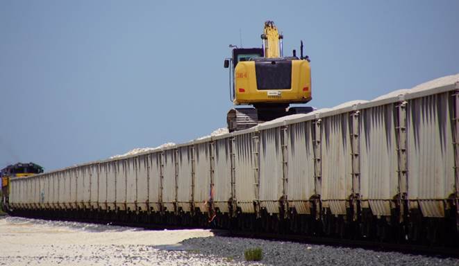 An excavator unloads Vulcan Materials Company’s first rail shipment of bulk aggregate to Port Freeport’s Parcel 14.