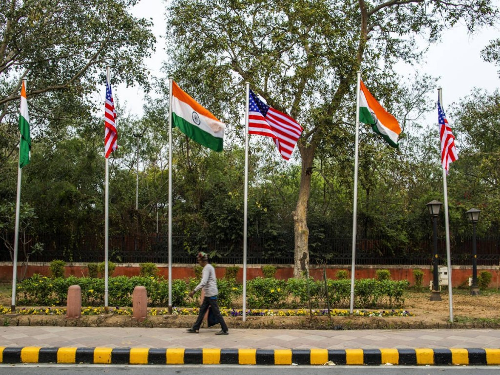 A pedestrian walks past American and Indian flags ahead of Trump’s arrival, in New Delhi, Feb. 23.Photographer: Prashanth Vishwanathan/Bloomberg