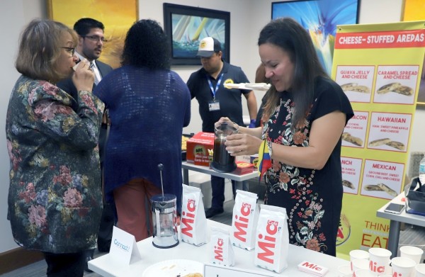 At the International Trade Hub at Port Manatee’s business development tour Aug. 23 event in Bradenton, Janna Strusberg Perdoma serves Café Mia beverages from Colombia while representatives of another Colombian company offer traditional arepa pastries.