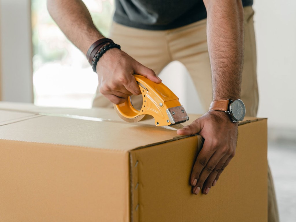 A person taping up a moving box, showing the main difference between freight and moving services.