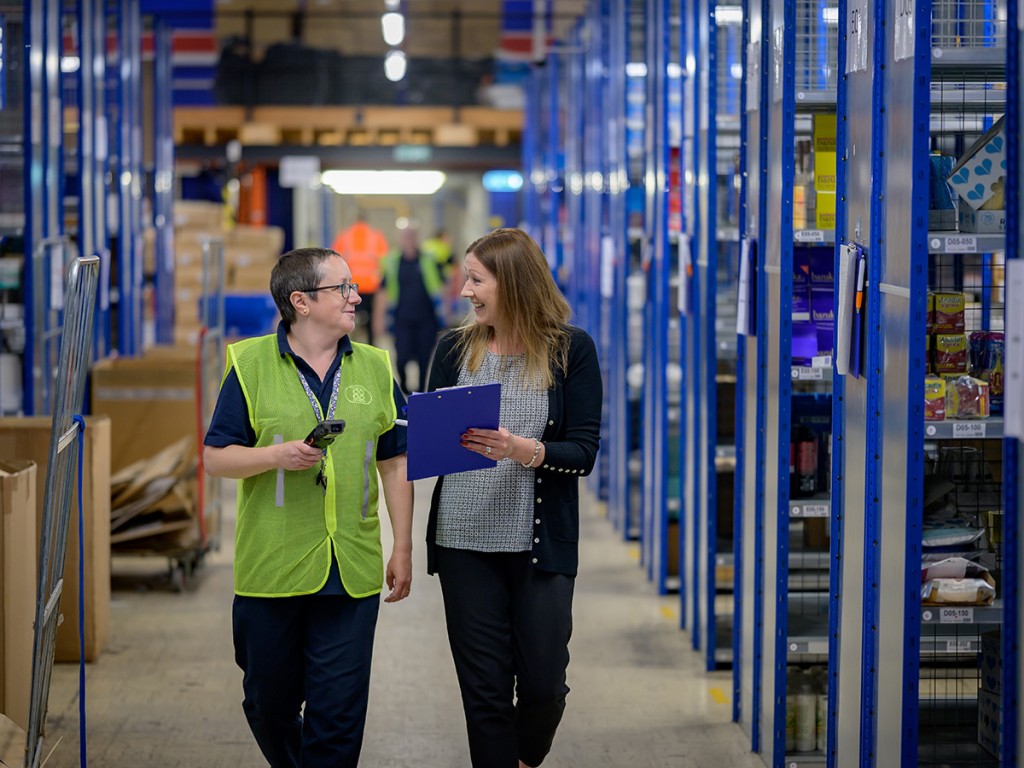 Two employees at a warehouse using CRM to enhance their customer-centric logistics services.